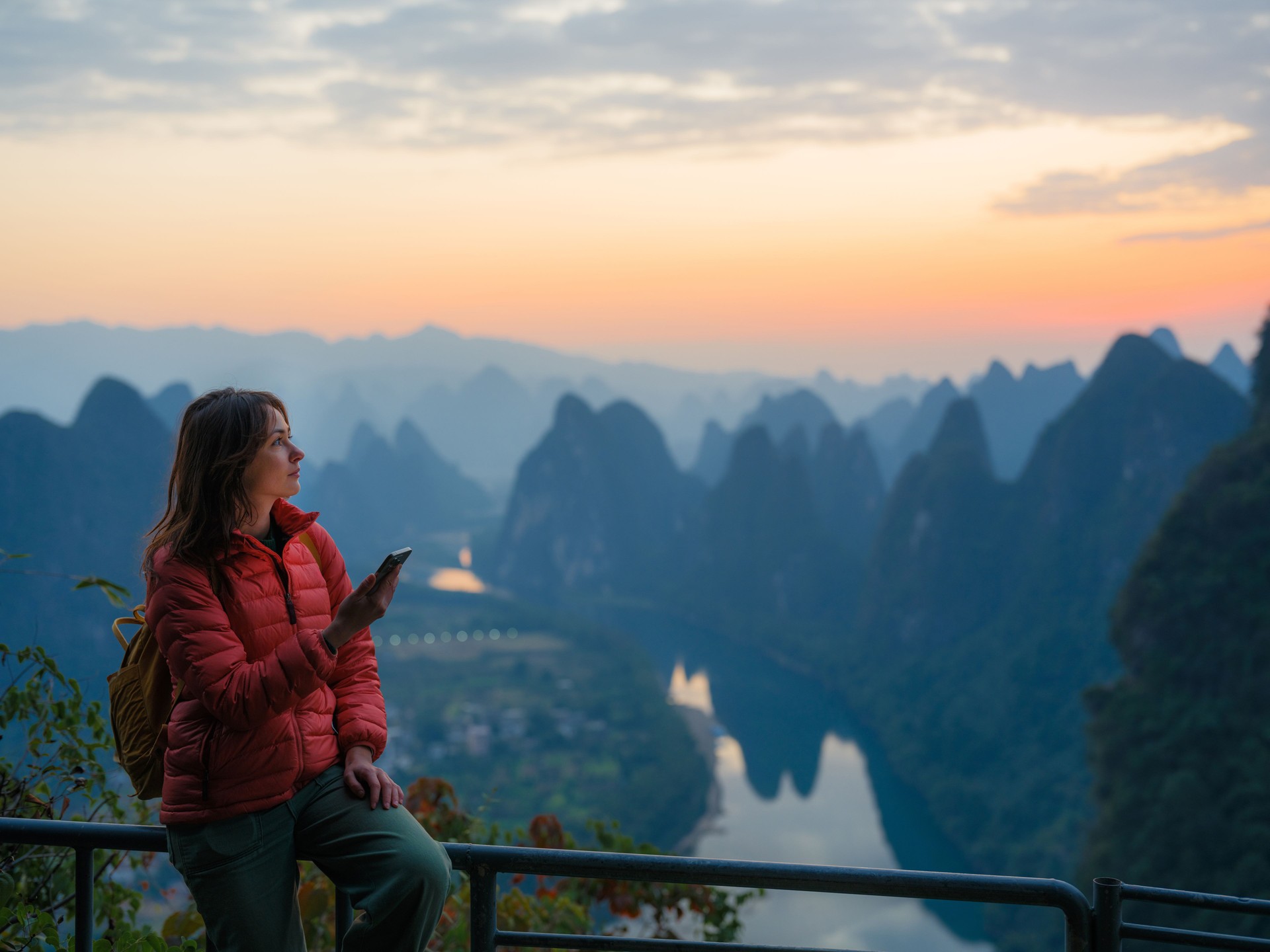 Woman using smartphone on viewpoint overlooking Li river in Guilin, China